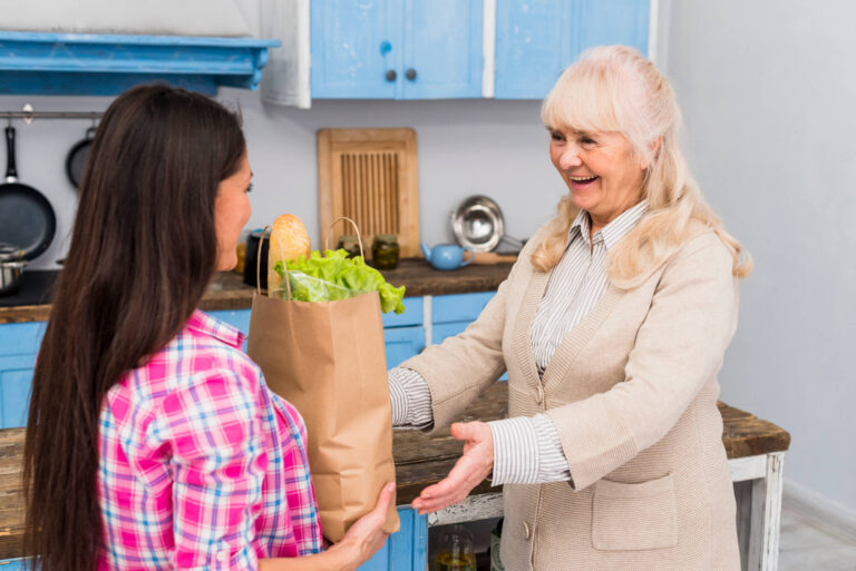 young-woman-giving-bag-groceries-her-senior-mother-kitchen (1) (1)